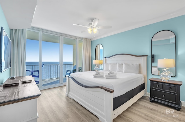 bedroom with a water view, access to exterior, light wood-type flooring, and floor to ceiling windows