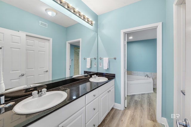 bathroom with double vanity, visible vents, a sink, and wood finished floors