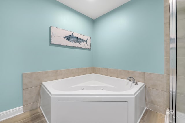 full bath with a whirlpool tub, wood finished floors, and tile walls