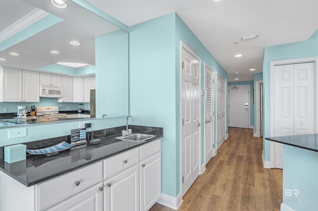 kitchen featuring recessed lighting, white appliances, a sink, white cabinetry, and light wood finished floors