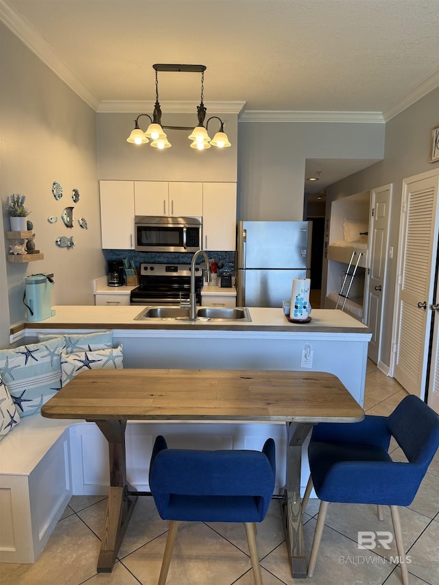 kitchen with a sink, crown molding, stainless steel appliances, and light tile patterned floors