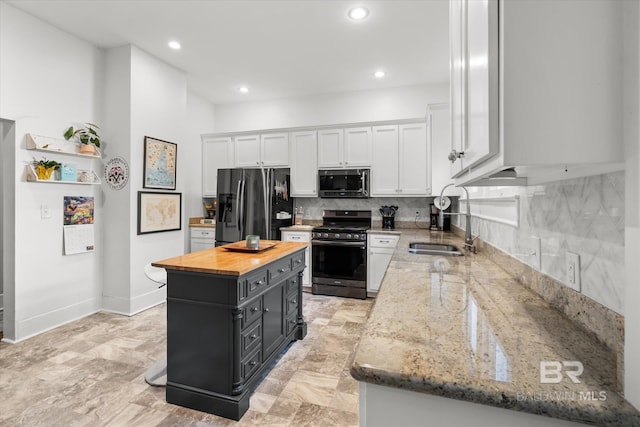 kitchen with a kitchen island, appliances with stainless steel finishes, sink, white cabinets, and butcher block countertops