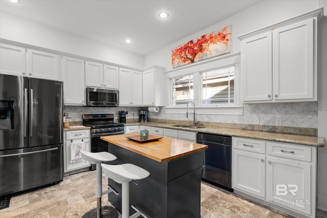 kitchen with stainless steel appliances, wood counters, sink, a center island, and tasteful backsplash