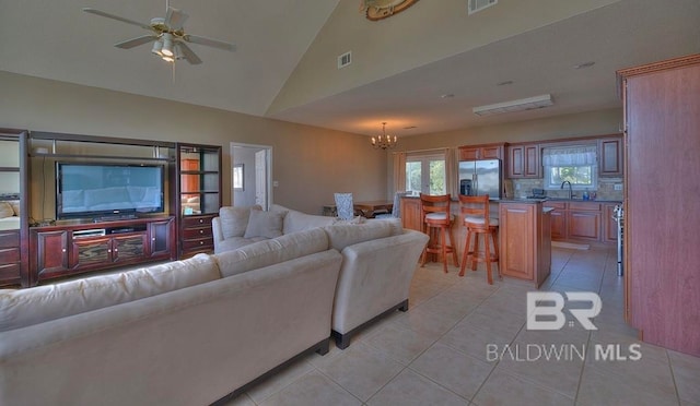 living room with ceiling fan with notable chandelier, vaulted ceiling, light tile flooring, and sink