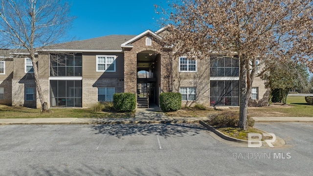 view of front of property featuring stairs, brick siding, and a front lawn