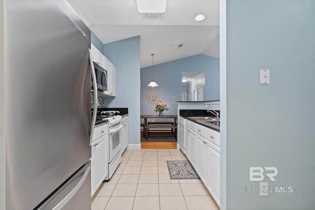 kitchen featuring light tile patterned floors, dark countertops, appliances with stainless steel finishes, white cabinetry, and a sink