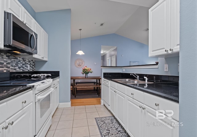 kitchen featuring light tile patterned floors, white appliances, a sink, white cabinets, and backsplash