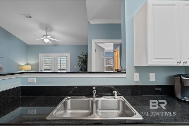 kitchen featuring dark countertops, white cabinetry, a sink, and visible vents