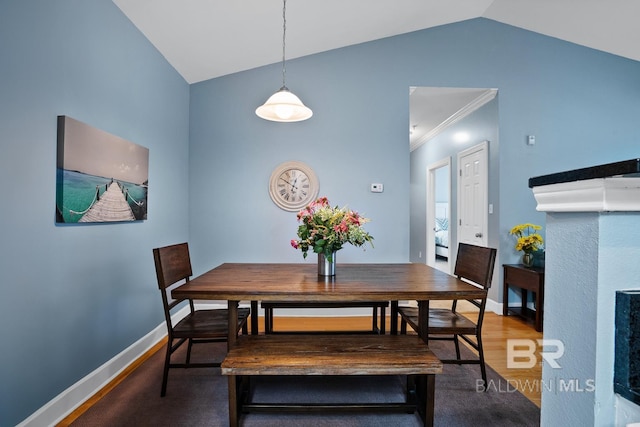 dining space with lofted ceiling, crown molding, baseboards, and wood finished floors