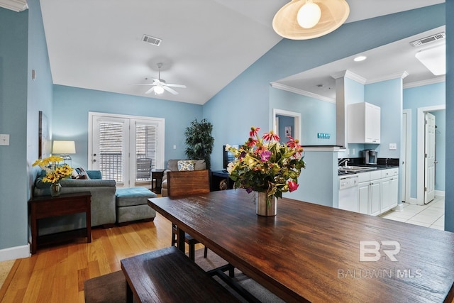 dining room featuring lofted ceiling, a ceiling fan, visible vents, light wood finished floors, and crown molding