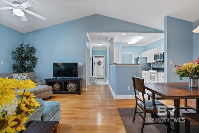 living room with lofted ceiling, a ceiling fan, baseboards, ornamental molding, and light wood-type flooring