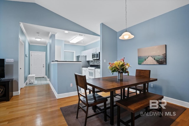 dining space with lofted ceiling, ornamental molding, light wood-type flooring, and baseboards