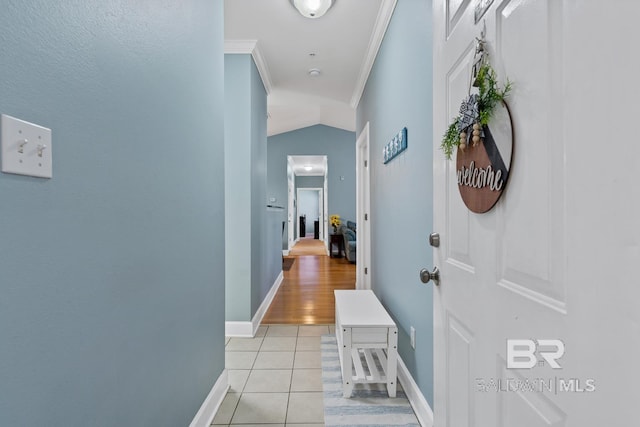 hallway with ornamental molding, light tile patterned flooring, and baseboards