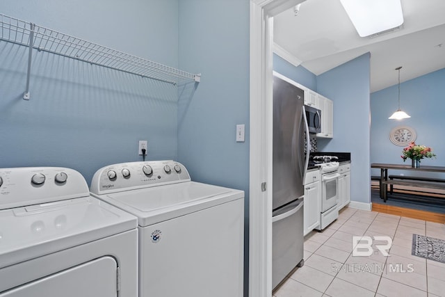 laundry room with light tile patterned floors, laundry area, separate washer and dryer, and baseboards