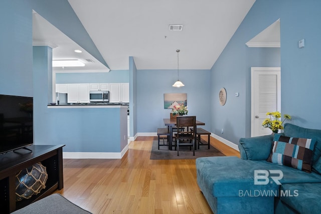 living room featuring a towering ceiling, light wood-style floors, baseboards, and visible vents