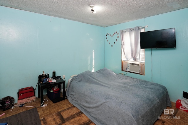 bedroom with cooling unit, parquet flooring, and a textured ceiling