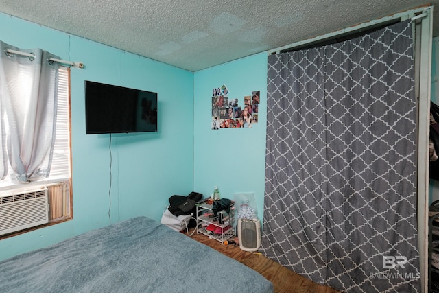 unfurnished bedroom featuring cooling unit, hardwood / wood-style floors, and a textured ceiling