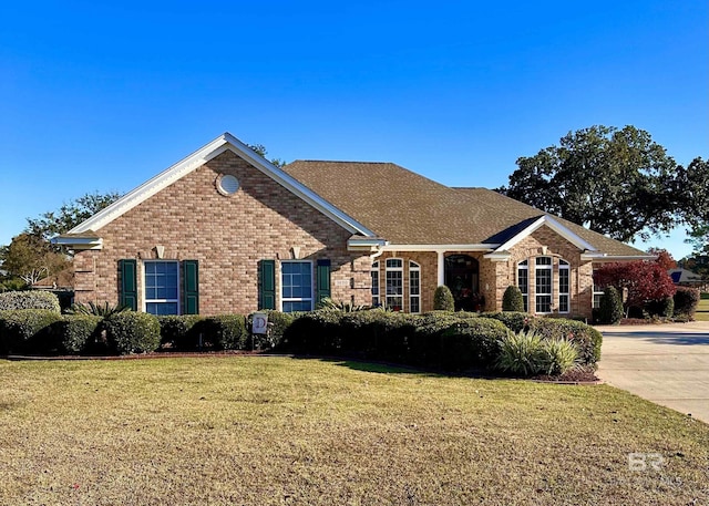 ranch-style home featuring driveway, a front lawn, and brick siding