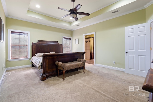 carpeted bedroom featuring a tray ceiling, crown molding, baseboards, visible vents, and a ceiling fan