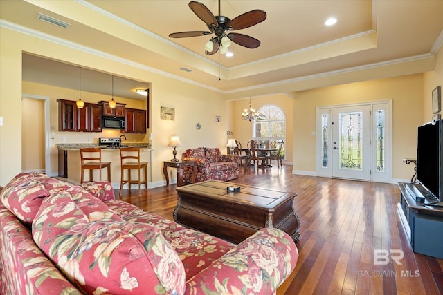 living room with hardwood / wood-style floors, a raised ceiling, ornamental molding, and visible vents