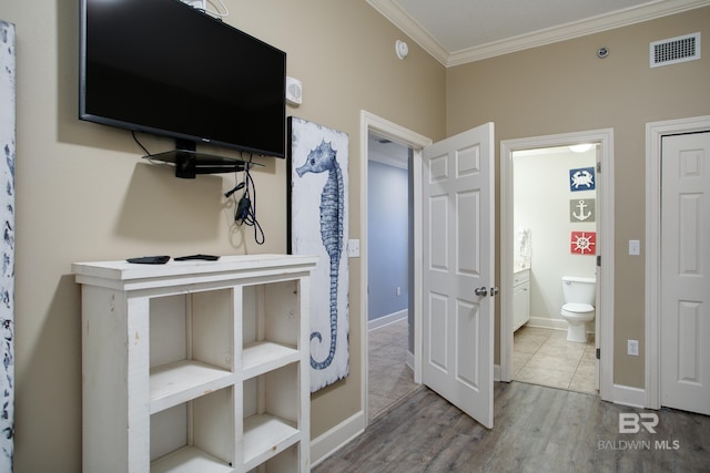 bedroom with visible vents, baseboards, wood finished floors, and crown molding