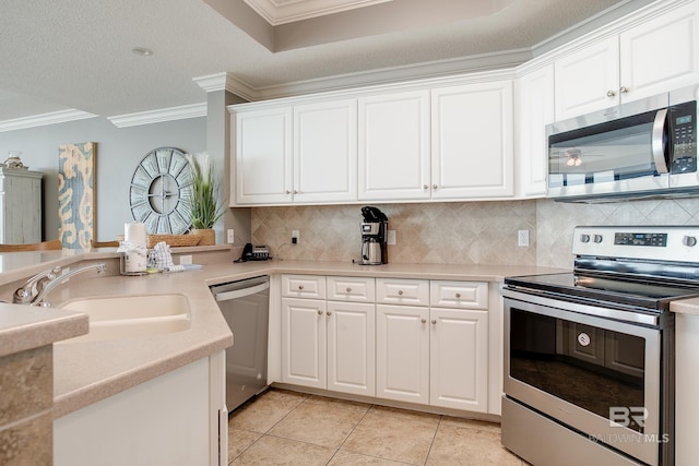 kitchen with a sink, ornamental molding, stainless steel appliances, white cabinets, and tasteful backsplash