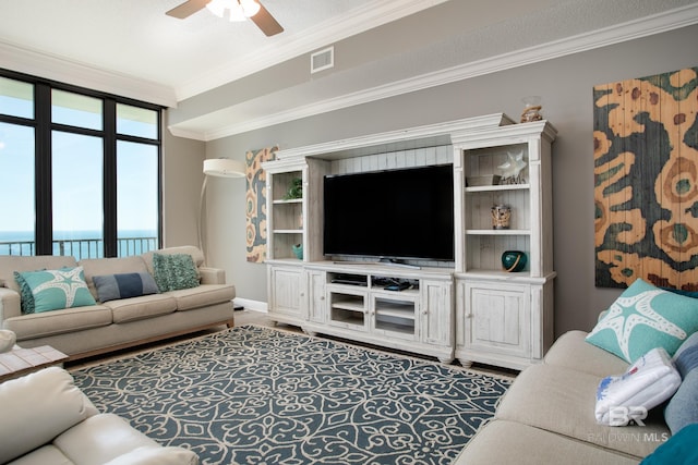 living room featuring visible vents, baseboards, a ceiling fan, and crown molding