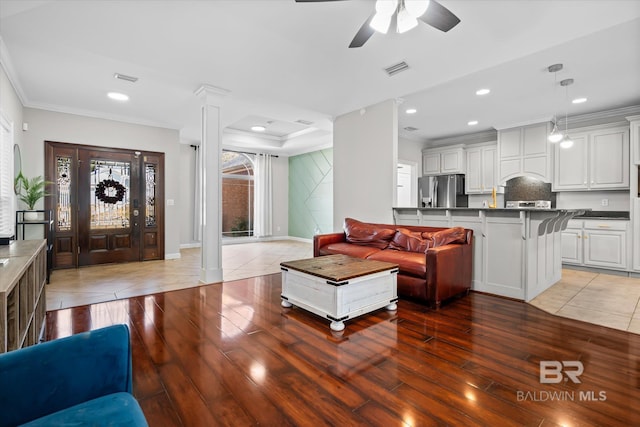 living room featuring ceiling fan, ornamental molding, light hardwood / wood-style floors, and decorative columns