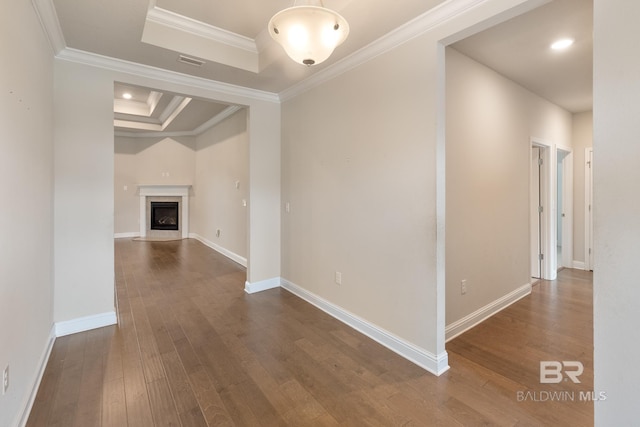 interior space featuring ornamental molding, a raised ceiling, baseboards, and wood finished floors