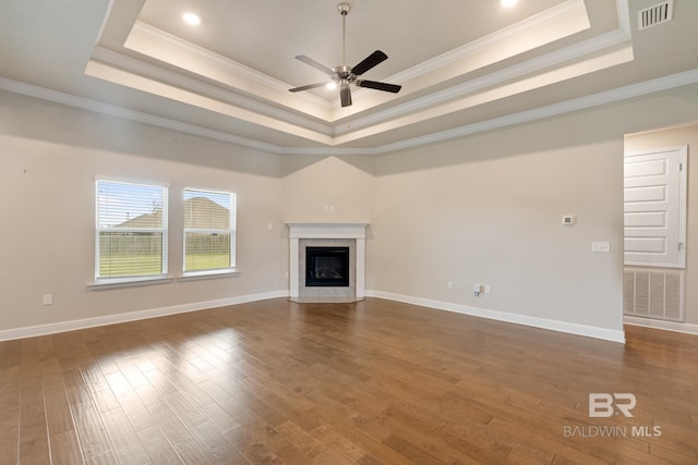 unfurnished living room featuring a fireplace, visible vents, dark wood finished floors, and a tray ceiling