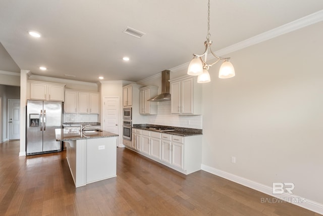 kitchen with visible vents, wall chimney exhaust hood, a kitchen island with sink, stainless steel appliances, and a sink