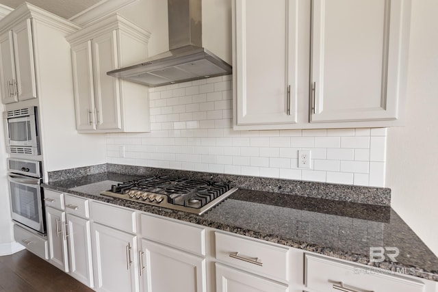 kitchen featuring white cabinets, stainless steel appliances, dark stone counters, and extractor fan