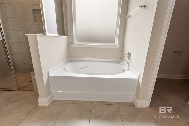 bathroom featuring a garden tub, tile patterned flooring, baseboards, and a shower stall