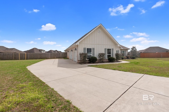 view of side of property with brick siding, fence, a yard, concrete driveway, and board and batten siding