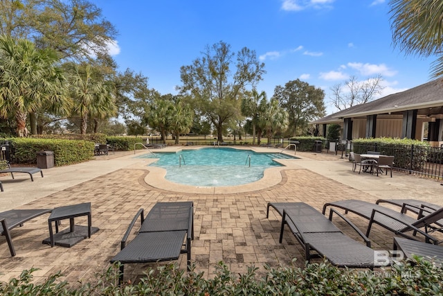 community pool with fence and a patio