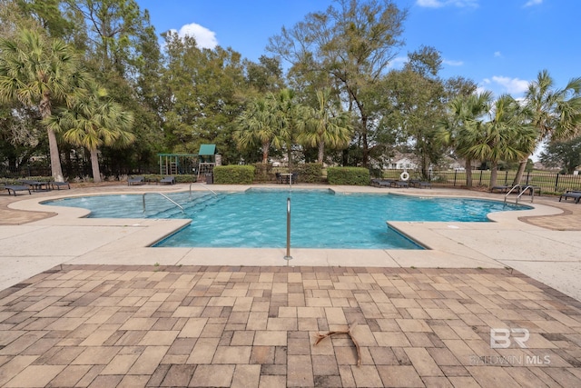 community pool with a patio area and fence