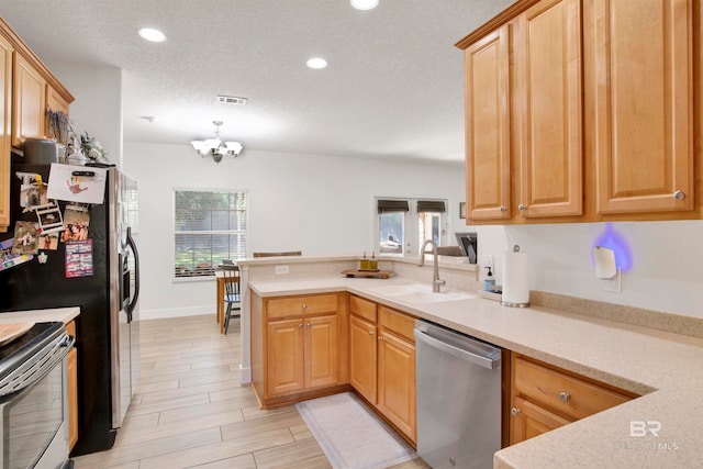 kitchen with kitchen peninsula, plenty of natural light, stainless steel appliances, and an inviting chandelier