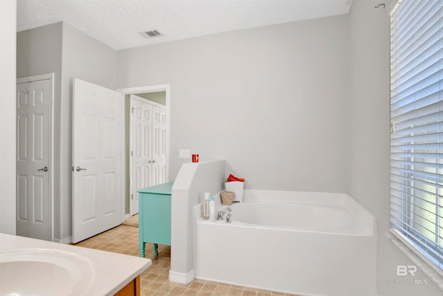 bathroom featuring a bathing tub, vanity, and a textured ceiling