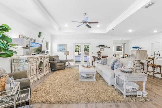 living area with ceiling fan, a raised ceiling, light wood finished floors, recessed lighting, and french doors