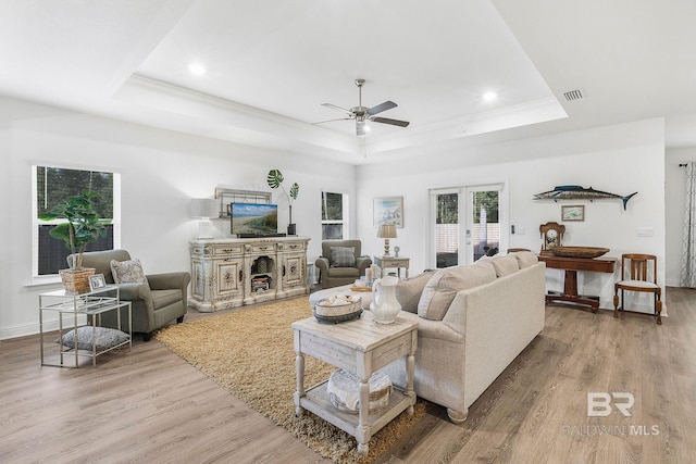 living area featuring a raised ceiling, ceiling fan, light wood finished floors, and recessed lighting