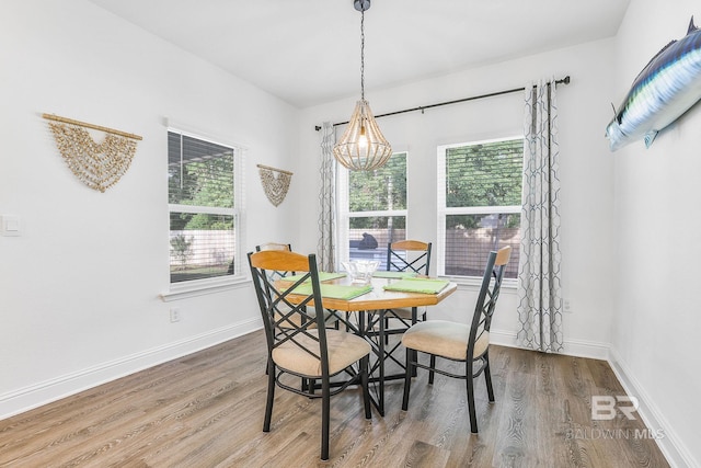 dining space featuring plenty of natural light, wood finished floors, a chandelier, and baseboards