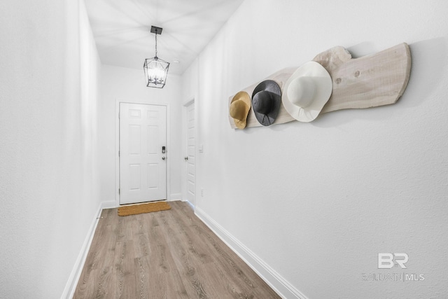 doorway with wood finished floors, a chandelier, and baseboards