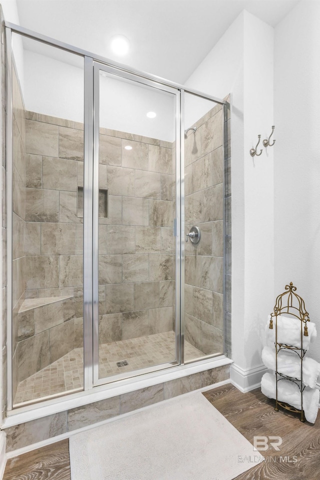 bathroom featuring a shower stall, wood finished floors, and baseboards