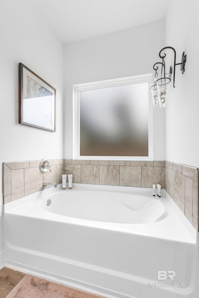 bathroom with a garden tub and wood finished floors