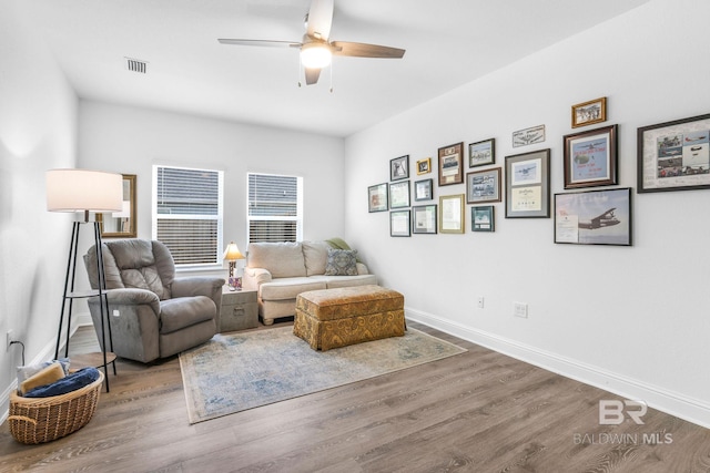 living area with wood finished floors, a ceiling fan, and baseboards