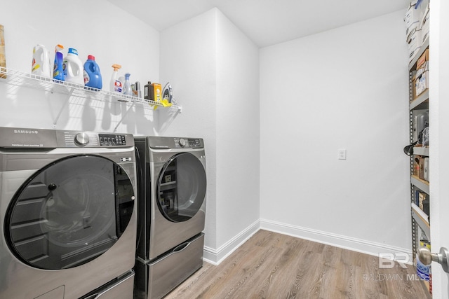 clothes washing area with independent washer and dryer, wood finished floors, and baseboards