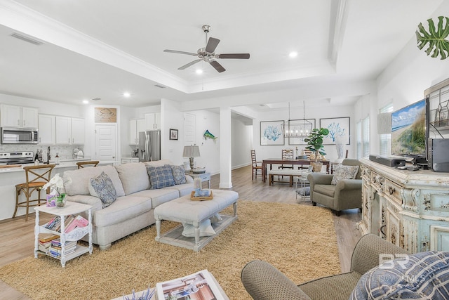 living area featuring light wood finished floors, ceiling fan, a raised ceiling, recessed lighting, and a chandelier