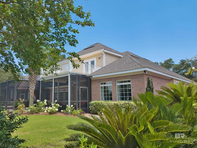 rear view of house with a balcony and a lawn