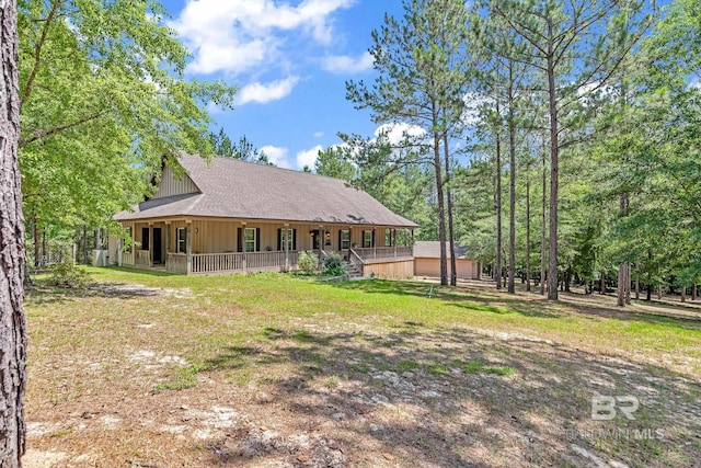 rear view of property with covered porch and a lawn