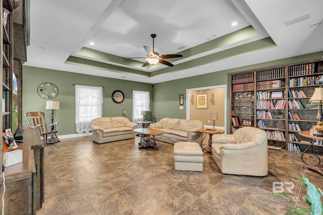 living room featuring a raised ceiling and ceiling fan